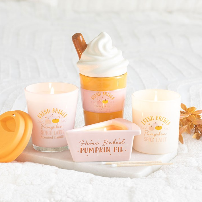 Set of candles with pumpkin-themed packaging on a white background