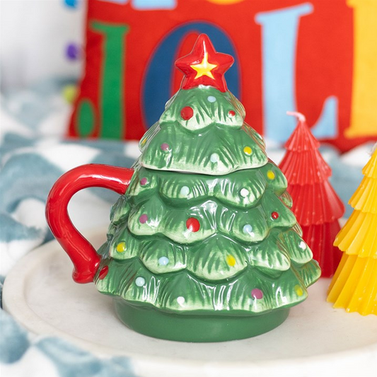 Green Christmas tree-shaped mug with a red handle on a white surface.