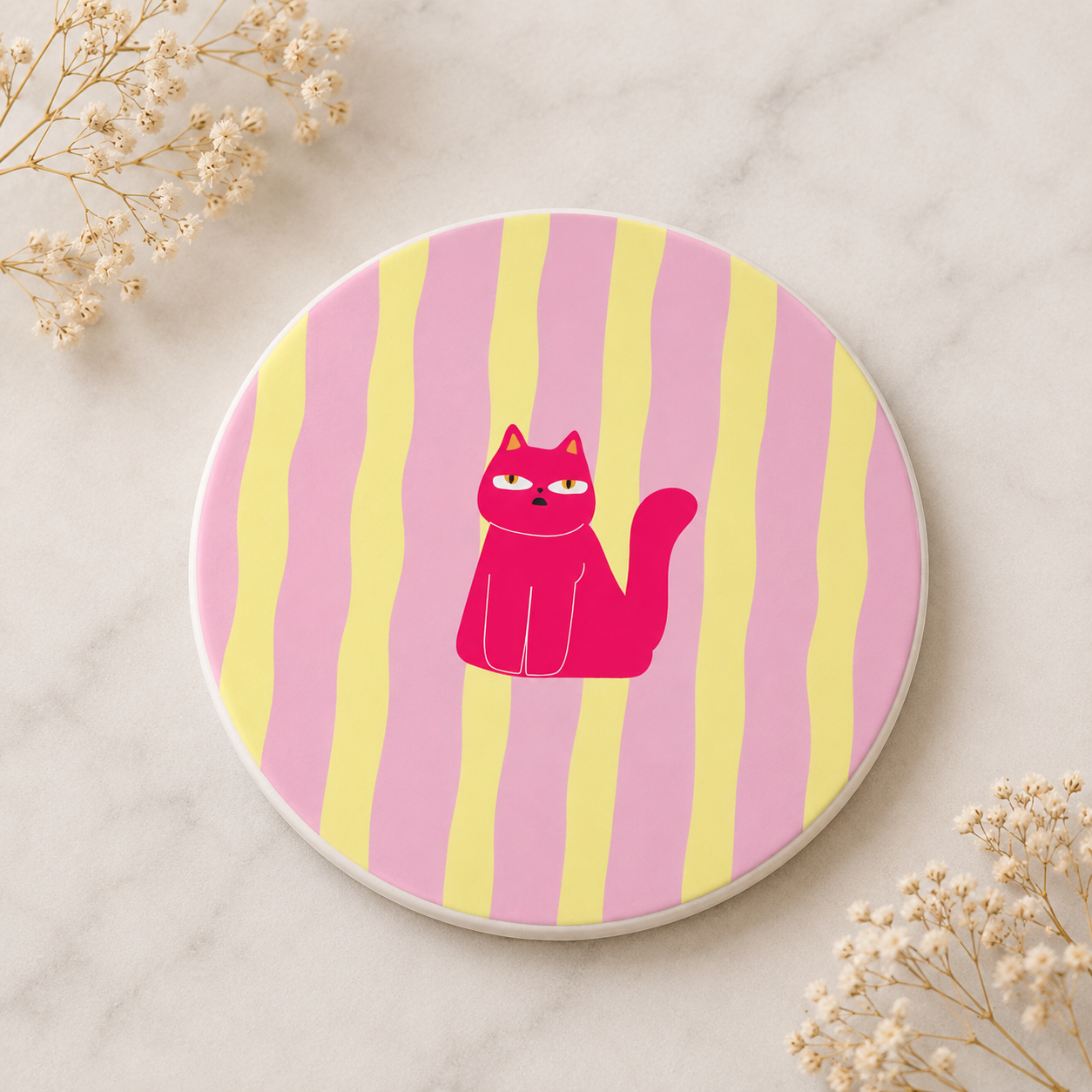 A ceramic coaster with a bright pink cartoon cat and pink and yellow stripes as the background