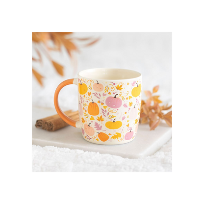 Mug with autumn-themed design featuring pumpkins and leaves on a white surface.