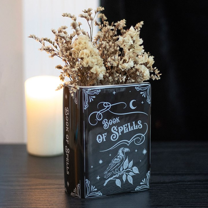 Decorative book titled 'Book of Spells' with dried flowers and a candle in the background