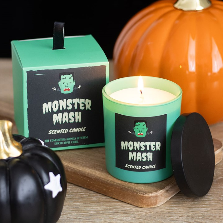 Monster Mash scented candle with packaging and decorative pumpkins on a wooden surface