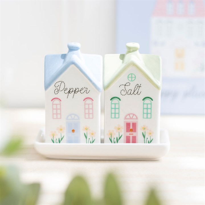 Salt and pepper shakers shaped like houses on a white plate with a blurred background